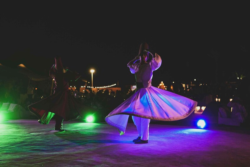 A person in a flowing dress performing on a stage with stage lights. 2