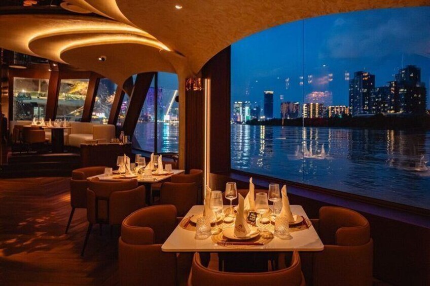 A restaurant with tables set for dinner, a city skyline view, and a body of water in the background. 2