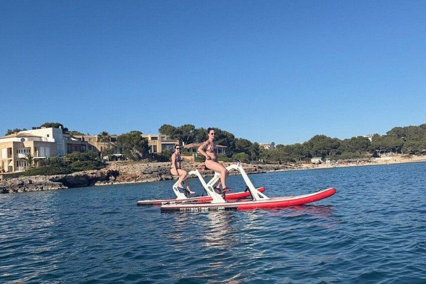 Two people on a red paddleboard in calm waters with buildings and trees in the background. 4