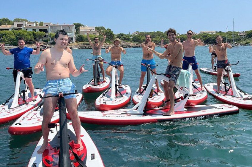 People paddleboarding on a calm body of water with buildings in the background. 1