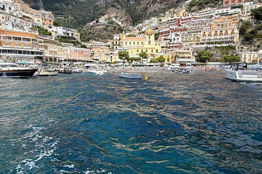 A coastal town with colorful buildings, a marina with boats, and a mountainous backdrop. 4