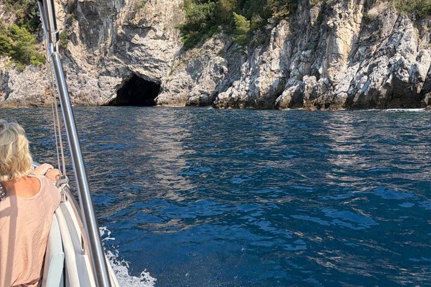 A boat navigating near a rocky coastline with a cave entrance. 2