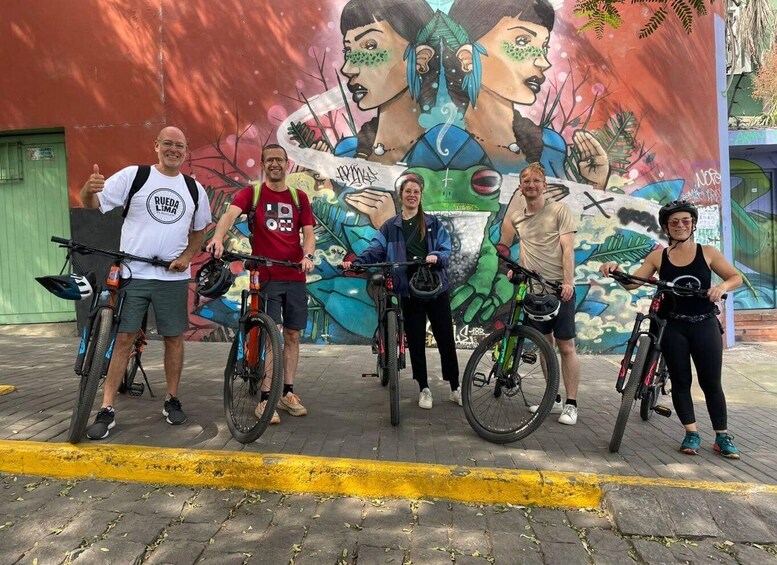 Un grupo de personas con bicicletas frente a un mural colorido. 2