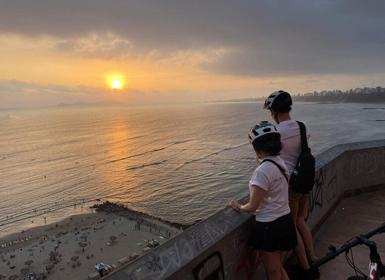 Atardecer sobre el océano, con gente en la playa y el perfil de una ciudad al fondo. 3