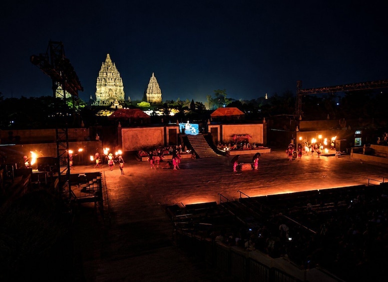 A nighttime outdoor performance with a stage, audience, and illuminated temple structures in the background. 4