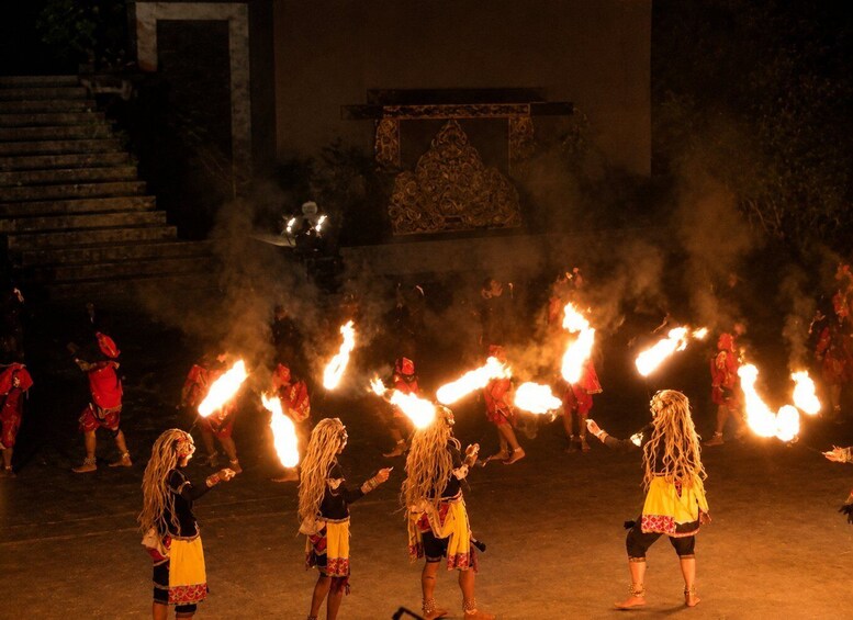 A nighttime cultural performance with performers carrying flaming torches. 5