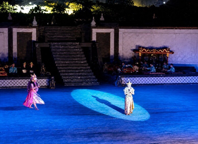 A stage with performers in traditional costumes, a staircase, and a seated audience. 3
