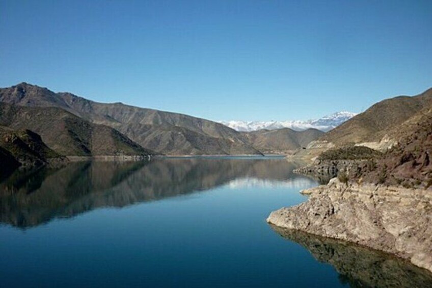 A calm lake surrounded by mountains with snow-capped peaks in the distance. 2