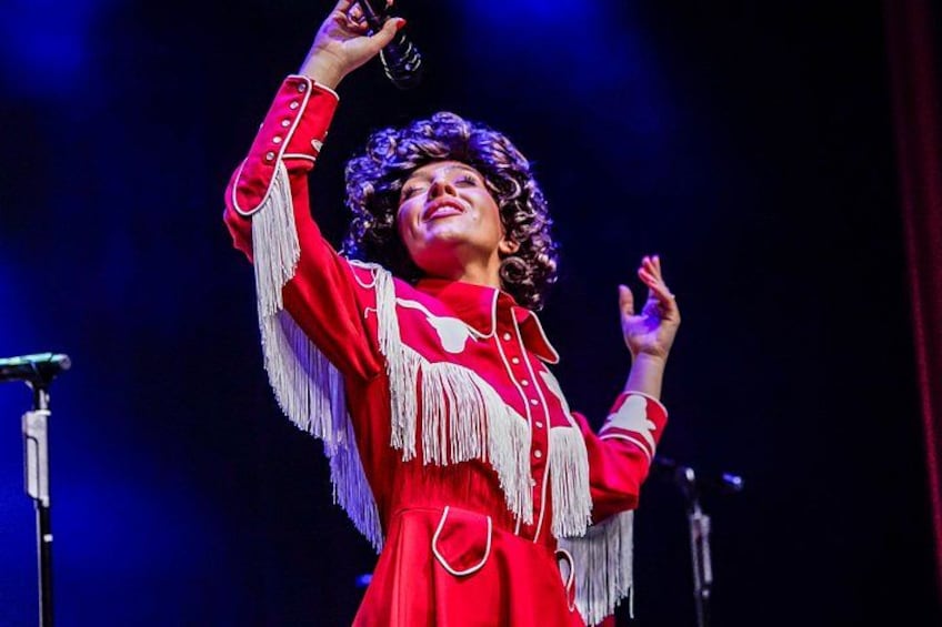 A person in a red dress with fringe details, holding a microphone. 4