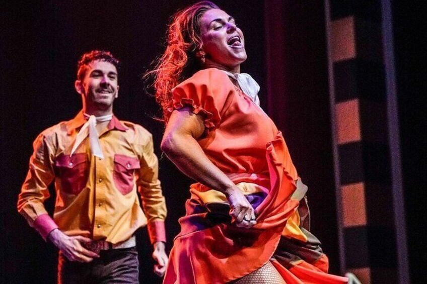 Two people in a performance setting, one in a yellow shirt and the other in a red dress. 5