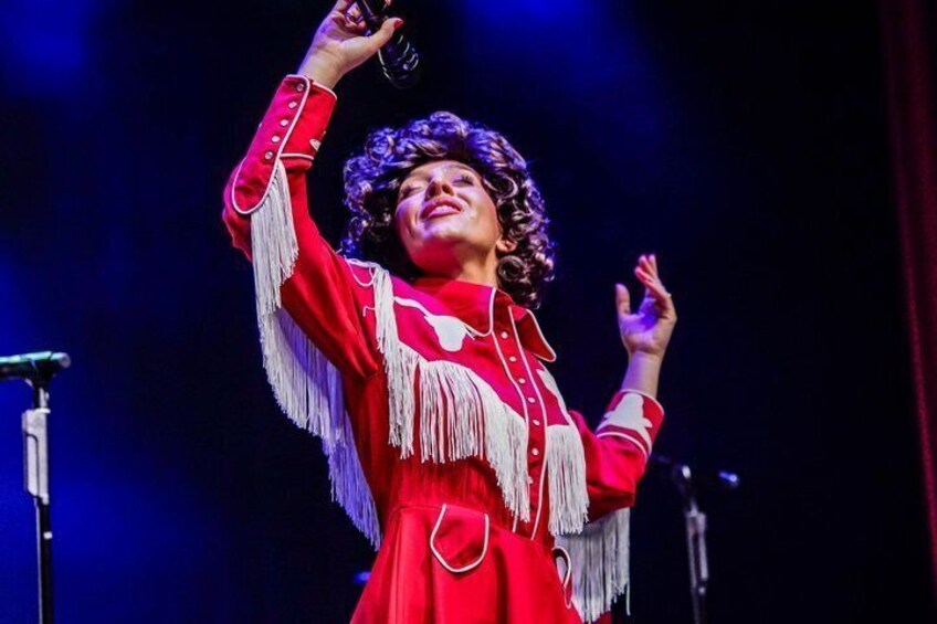 A person in a red dress with fringe details, holding a microphone. 3