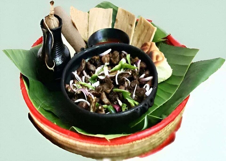 A traditional dish in a red bowl with a black lid, accompanied by flatbreads and a small black container, possibly a condiment. 3