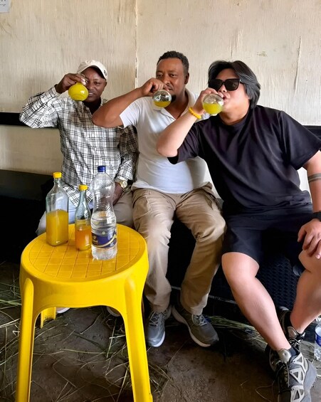 Three people sitting on a bench, drinking from yellow bottles. 2
