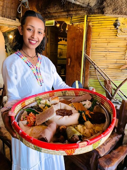 A person holding a large woven tray with various foods. 1