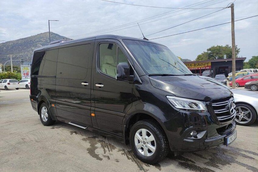 A black van parked on a concrete surface with a mountain in the background. 3