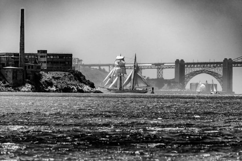 A river with a bridge, a sailboat, and industrial buildings. 3