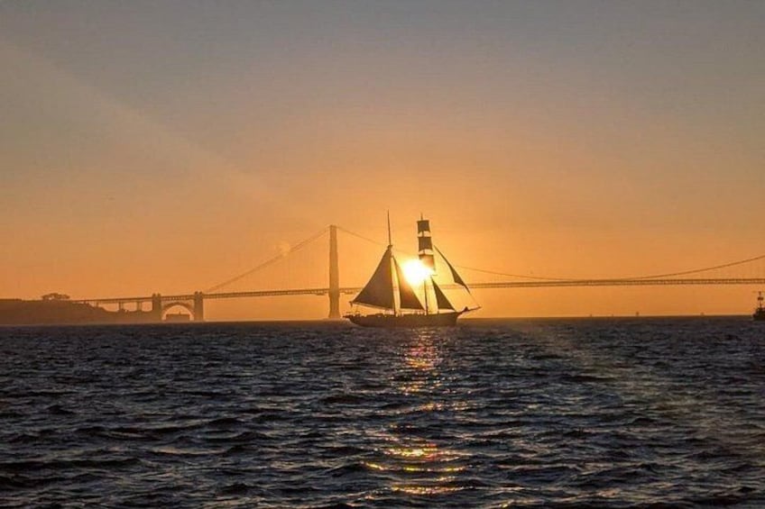 A sailboat on the water with a bridge in the background. 1