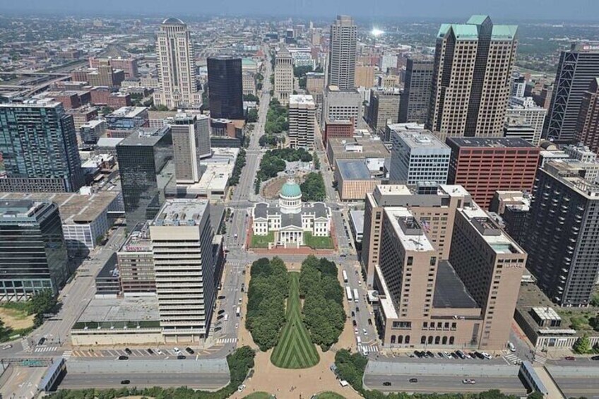 A cityscape with modern high-rise buildings, a central green park, and a prominent dome structure. 2