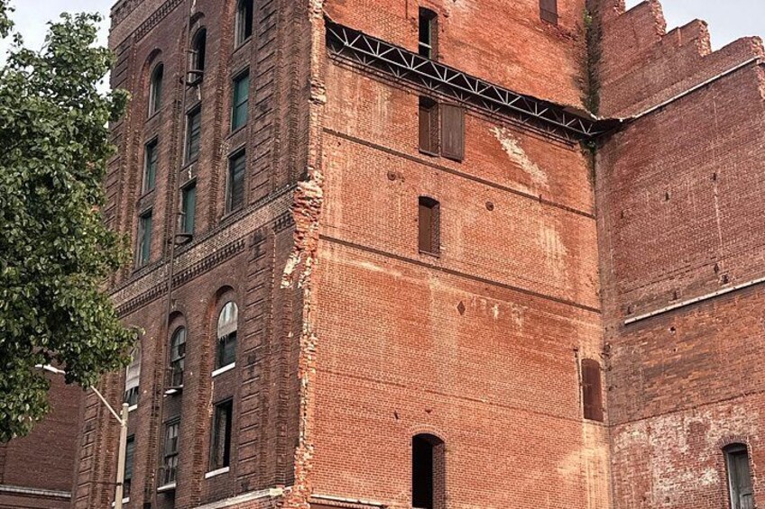 A historic brick building with arched windows and a metal framework. 1