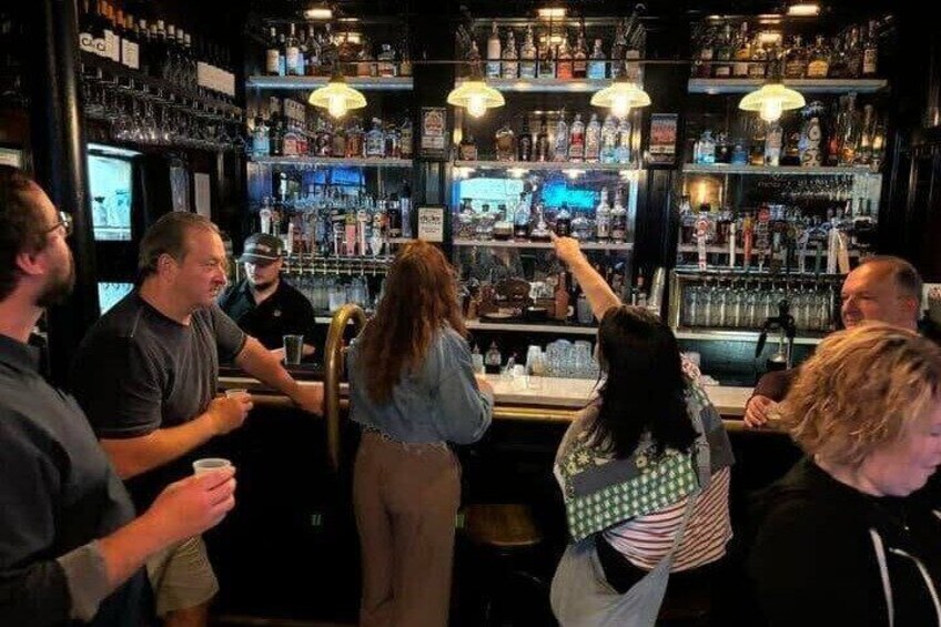 A bar with shelves of bottles and a person pointing at something. 5