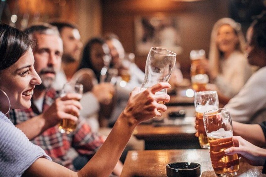 A group of people toasting with beer glasses at a bar. 2