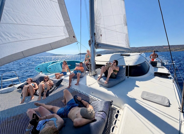 A sailboat with people lounging on deck, a clear blue sky, and calm waters. 5