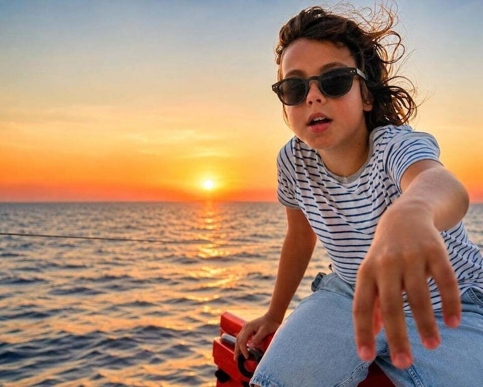 A person sitting on a red chair by the ocean during sunset. 1