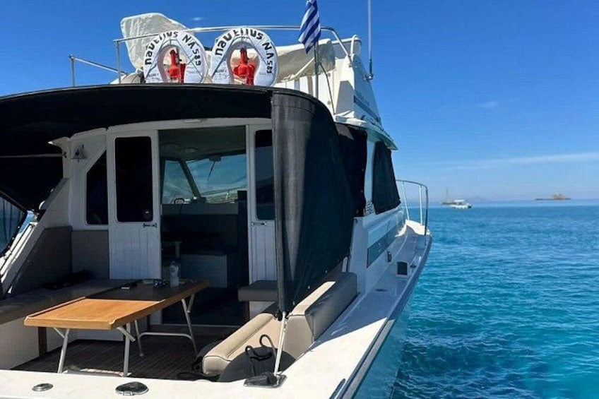 A boat with a table and chairs, a flag, and a clear blue sea. 2