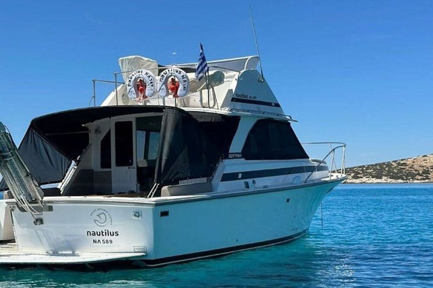 A white boat named 'nautilus' with registration number NA 589, docked in clear blue water. 3