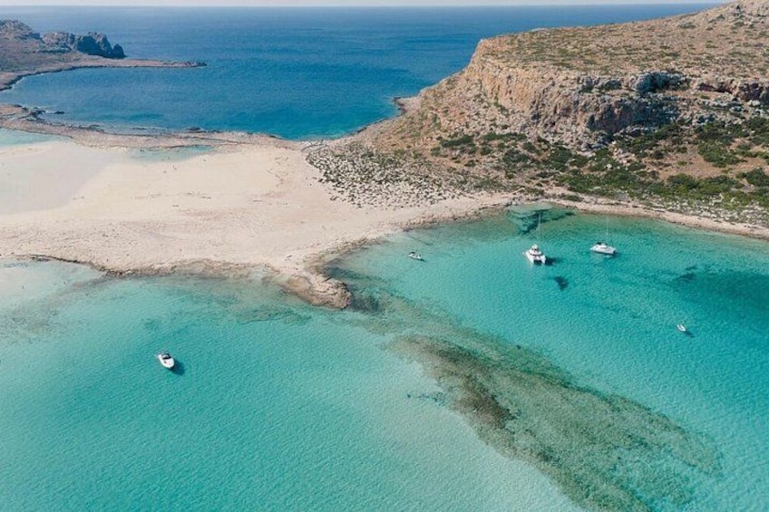 A coastal landscape with clear turquoise waters, a sandy beach, and rocky cliffs. 4