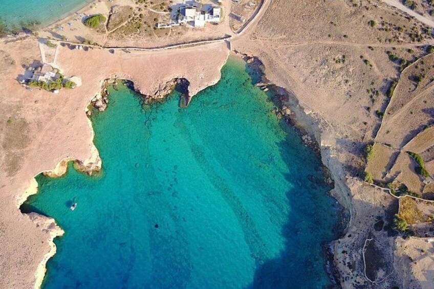 A coastal landscape with a clear blue sea, sandy beaches, and scattered buildings. 1