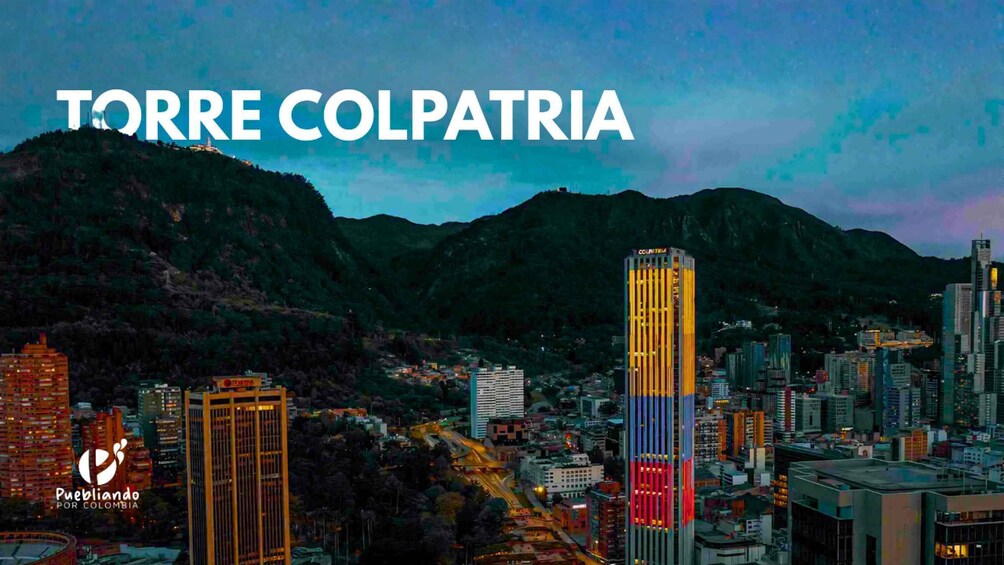 A cityscape with the Torre Colpatria prominently featured in the center, surrounded by other buildings and mountains in the background. 1