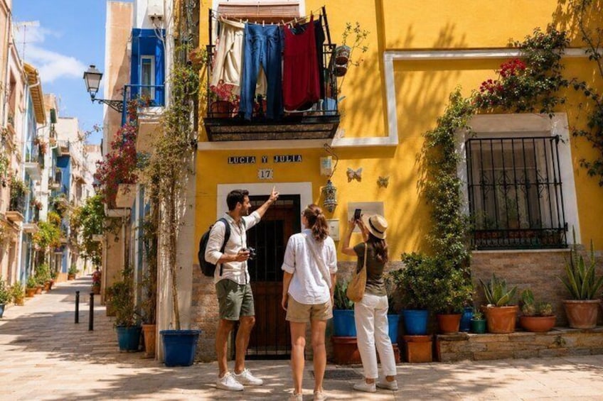 A narrow street with buildings, potted plants, and a sign with the number 17. 1