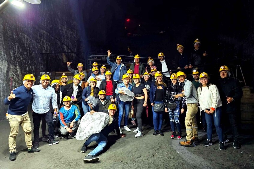 A group of people in hard hats gathered in a dimly lit underground area. 4