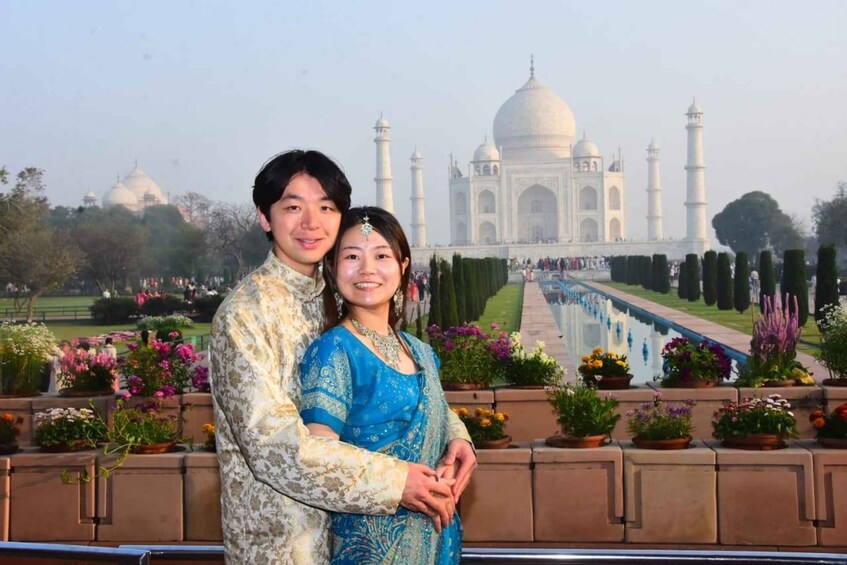 A couple standing in front of the Taj Mahal with a garden and pathway in the background. 5