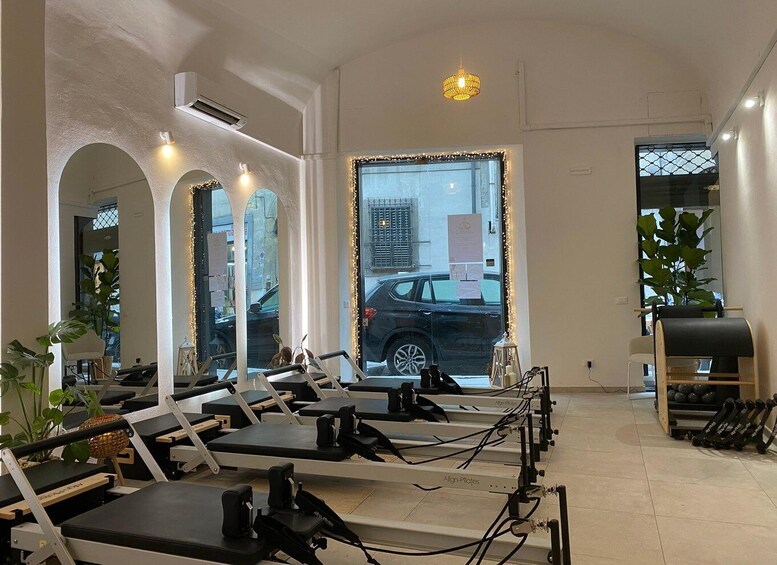A Pilates studio with equipment, mirrors, and a view of the street outside. 3