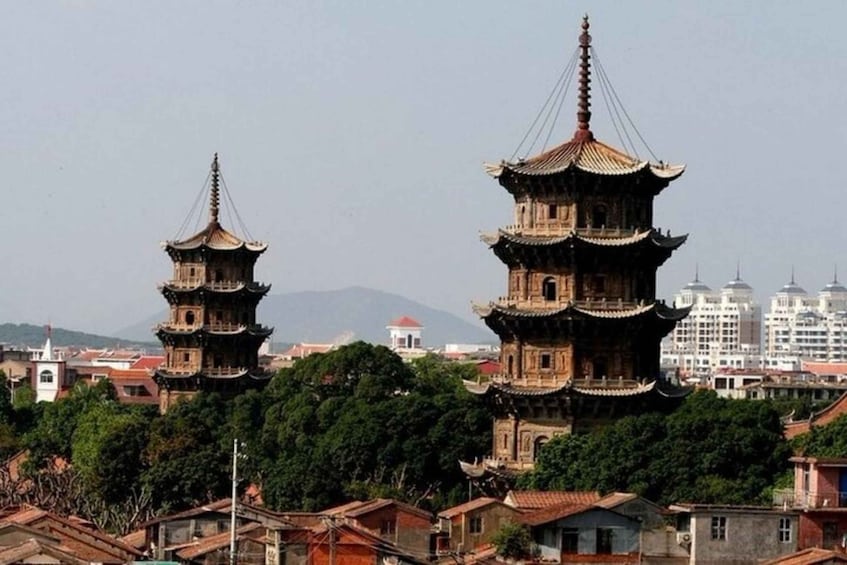 A traditional pagoda-style building with multiple tiers, surrounded by trees and residential buildings. 1