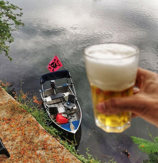 A small boat with a skull and crossbones sign, a glass of beer, and a calm water body. 3