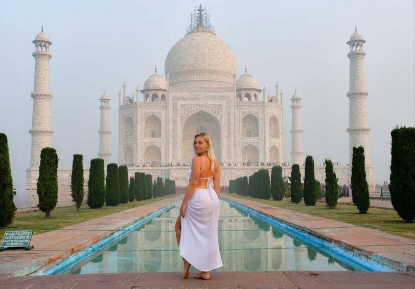 En kvinna i en vit klänning som står framför Taj Mahal. 1