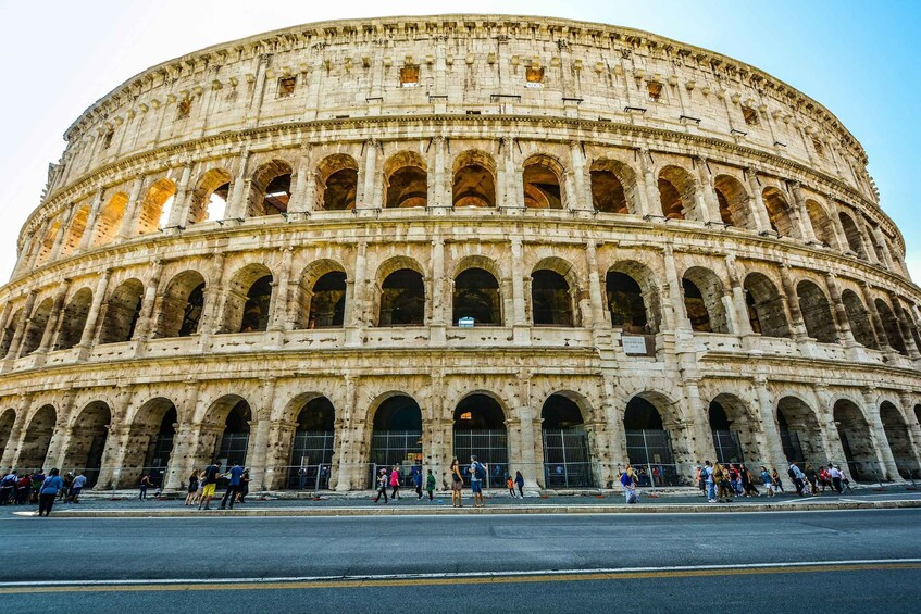 The Colosseum with multiple arches and tourists. 5