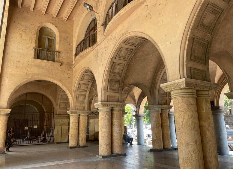 Un interno caratterizzato da archi e colonne, una persona che cammina e un'altra seduta. 5
