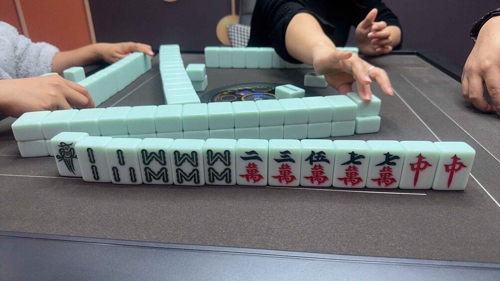 A game of Mahjong with tiles arranged on a table. 5