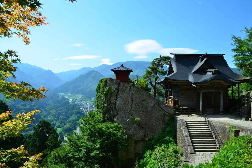 A traditional Japanese temple on a mountain with a view of a valley below. 1