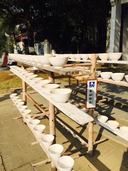 A display of white bowls on wooden racks outdoors. 3