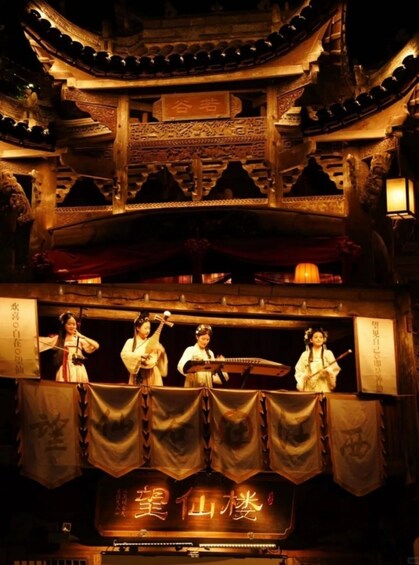 A traditional Chinese stage with performers in period costumes, a wooden stage structure, and a banner with Chinese characters. 5