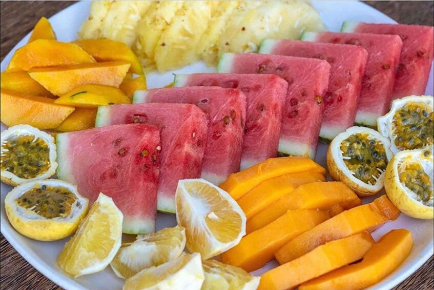 A plate of sliced fruits including watermelon, passion fruit, mango, and pineapple. 3