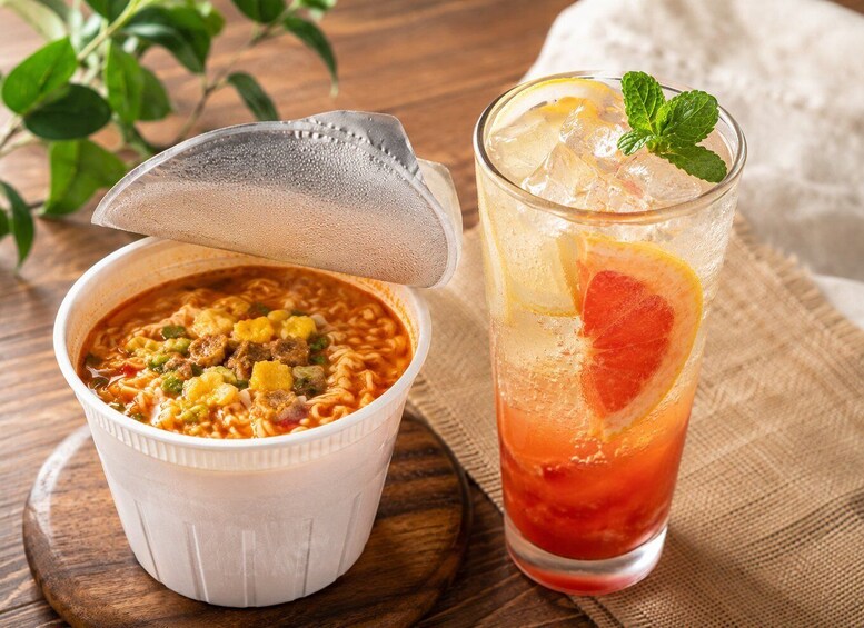 A bowl of soup with a lid and a glass of iced drink with a slice of fruit and mint. 5