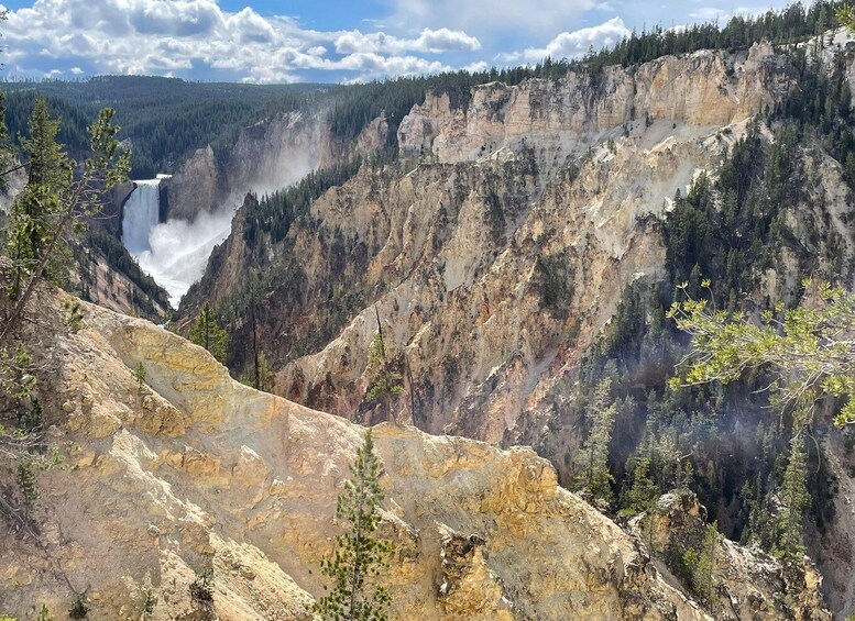 A canyon with a waterfall, surrounded by forested mountains. 3