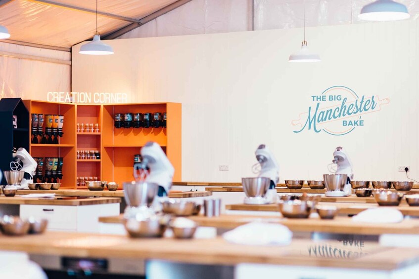 A bakery interior with shelves of baking ingredients and mixers on countertops. 3
