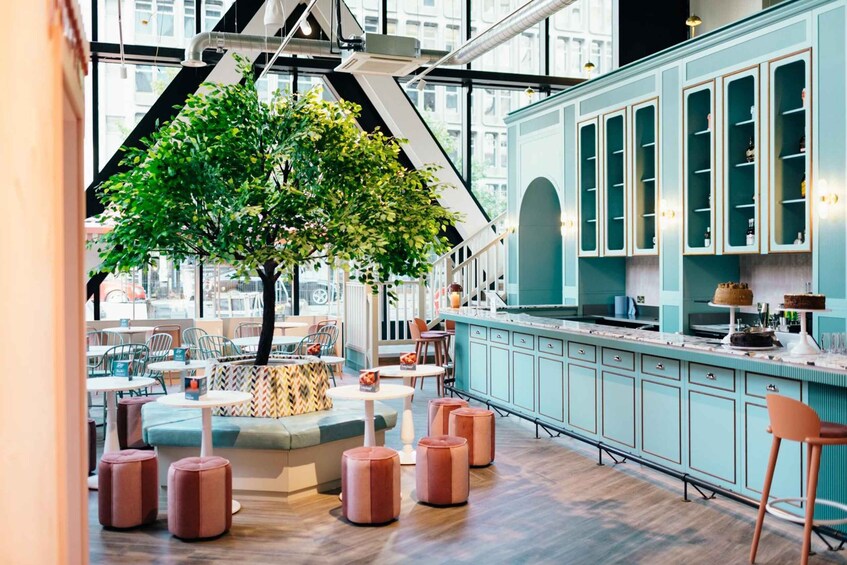 A modern interior with teal cabinetry, a central tree, and seating areas. 4